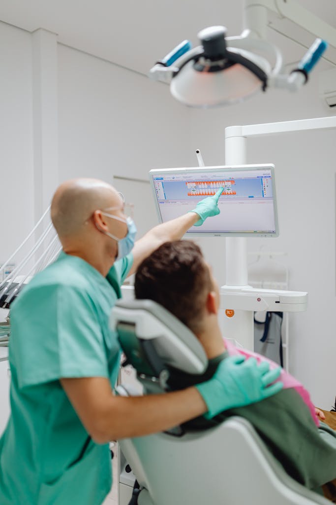 Dentist and patient discussing dental treatment with a digital screen display.